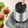 A finger presses a button on the lid of a food processor, with meatballs and lettuce in the background. Produktbild-Vorschau