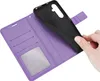 A hand is holding a black phone case over an open purple wallet case with card slots and a clear window. Produktbild-Vorschau