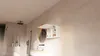 A modern bathroom with a hanging wall cabinet open, revealing toiletries, a mirror, a sink, and a shower. Produktbild-Vorschau