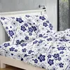 A bed with white bedding featuring a blue floral pattern. Produktbild-Vorschau