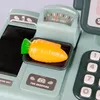 A close-up view of a toy cash register with a toy carrot on the scale. Produktbild-Vorschau