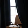 A chair with an open book in front of a window with dark blue curtains. Produktbild-Vorschau