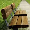 A wooden bench sits next to a wooden boardwalk, surrounded by tall green grass. Produktbild-Vorschau