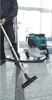A person is vacuuming a floor with a Makita canister vacuum cleaner. Produktbild-Vorschau