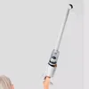 Weißer Handstaubsauger mit langer Verlängerung und Bürstenaufsatz, von einer Hand gehalten Produktbild-Vorschau