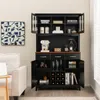 A black hutch-style cabinet with glass doors and wooden accents, filled with various items like a coffee maker, books, and wine bottles, placed in a room setting next to a sofa. Anteprima dell’immagine prodotto
