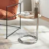 A side table with a glass top is placed next to an armchair, with a book and a cup of coffee on it. Anteprima dell’immagine prodotto