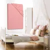 A pink fitted sheet is displayed against a white background, with a bed and bedroom furniture in the background. Produktbild-Vorschau