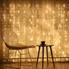 A chair and a small table are placed in front of a curtain decorated with warm white string lights. Anteprima dell’immagine prodotto
