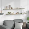Two shelves mounted on a white wall above a gray sofa, decorated with various items. Produktbild-Vorschau