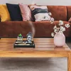 A Zen garden with a Buddha head and a small cactus is placed on a wooden coffee table in front of a sofa. Náhled obrázku produktu