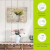 A wall clock with a floral design is displayed on a white paneled wall, with a vase of flowers below it. To the right, a green overlay highlights product features and warranty information. Produktbild-Vorschau