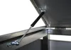 A close-up view of a gas strut supporting an open lid of a metal container. Náhled obrázku produktu