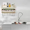 A gold wine rack mounted on a white wall above a kitchen counter with a sink and faucet. Podgląd zdjęcia produktu