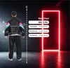 A person wearing a tracksuit stands in front of a brick wall with a neon light frame. A size chart is displayed next to the person. Voir les images du produit