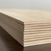 A stack of thin wooden boards, likely plywood, is shown from a side angle, resting on a dark wooden surface. Produktbild-Vorschau