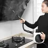 A person is using a handheld steam cleaner to clean a kitchen stovetop and hood. Produktbild-Vorschau