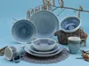 A collection of blue ceramic dishes and a mug are arranged on a blue background, with decorative branches overhead. Náhľad obrázku produktu