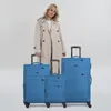 A woman stands behind a set of three blue suitcases. Voir les images du produit