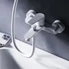 A white bathtub faucet mounted on a gray tiled wall, with a white shower hose and a white smartphone in the foreground. Produktbild-Vorschau