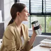 A woman is holding a coffee maker and smiling. Produktbild-Vorschau