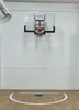 A basketball hoop mounted on a white wall above a basketball court. Produktbild-Vorschau