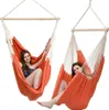 Two women relaxing in orange hammock chairs against a white background. Podgląd zdjęcia produktu