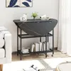 A foldable dining table with shelves is shown in a room setting, next to a sofa and a window. Anteprima dell’immagine prodotto