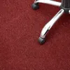 A close-up view of the base of an office chair with wheels on a dark red carpet. Anteprima dell’immagine prodotto