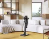 A modern living room with a sectional sofa, a bookshelf, and a vacuum cleaner. Produktbild-Vorschau