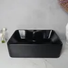 A black washbasin is displayed on a marble countertop against a gray wall. Podgląd zdjęcia produktu