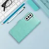 A teal book-style phone case is shown on a light blue background, with a keyboard, glasses, and pens in the background. Náhled obrázku produktu
