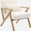 A white fluffy armchair with wooden legs and armrests, shown against a plain white background. Produktbild-Vorschau