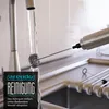 A handheld frother is being rinsed under a running faucet in a kitchen sink. Produktbild-Vorschau