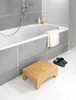 A bathroom scene with a bathtub, a wooden stool, and a pair of slippers. Produktbild-Vorschau