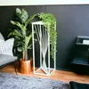 A modern living room setting with a plant stand, a large plant, and a chair. Anteprima dell’immagine prodotto