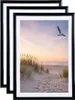 Three black picture frames are stacked on top of each other, with the front frame displaying a beach scene at sunset. Produktbild-Vorschau