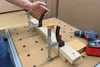 A person is using clamps to hold two pieces of wood together on a workbench. A drill is also visible. Anteprima dell’immagine prodotto