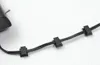 A close-up shot of black cable clips attached to black wires on a white textured surface. Náhľad obrázku produktu