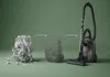 A vacuum cleaner is shown next to a pile of debris that has been broken down into smaller pieces, illustrating the cleaning process. Produktbild-Vorschau