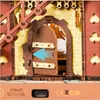 A close-up view of a wooden 3D puzzle, specifically a cuckoo clock, showing an open door with a blue arrow indicating movement. The bottom of the image shows input specifications and regulatory symbols. Náhľad obrázku produktu