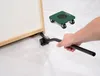 A hand is using a tool to lift the corner of a large object, with a furniture dolly in the background. Produktbild-Vorschau