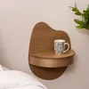 A wooden shelf mounted on a wall next to a bed, with a mug on the shelf. Produktbild-Vorschau