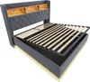 A bed frame with a lifted mattress support, revealing storage space underneath. The headboard has integrated lighting and wooden accents. Produktbild-Vorschau