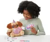 A young girl is playing with a plush toy dog that has a unicorn horn. She is holding a syringe-like object and appears to be feeding the toy. Anteprima dell’immagine prodotto