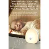 A baby sleeping next to a glowing night light with musical notes floating around it. Produktbild-Vorschau