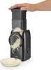 A hand is pressing down on the top of a black electric grater, which is grating cheese into a bowl. Produktbild-Vorschau