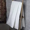 A white duvet is draped over a wooden ladder against a concrete wall. A patterned textile hangs on the left. Produktbild-Vorschau