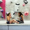 Zwei Frauen sitzen auf einer Klettermatte und genießen Getränke aus dem "Climbing Mug" von YY Vertical. Podgląd zdjęcia produktu