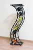 A black metal wine rack with several bottles of wine is standing against a light-colored wall. Anteprima dell’immagine prodotto